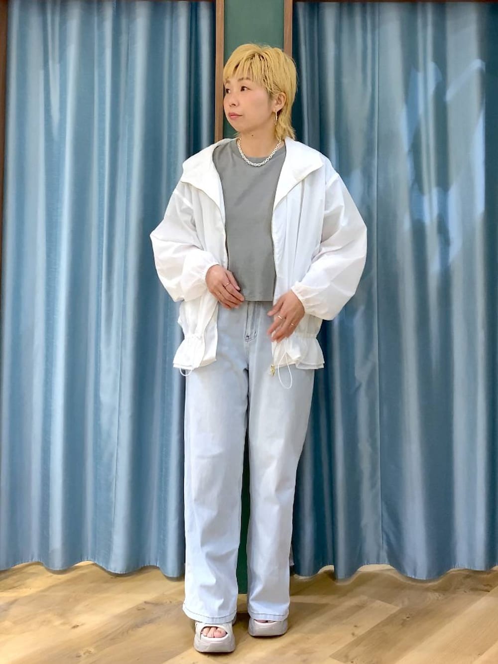 ブルー系のデニムパンツ、グレー系のサンダル、ホワイト系のブルゾンを着用したレディースの春コーディネートの3枚目の写真