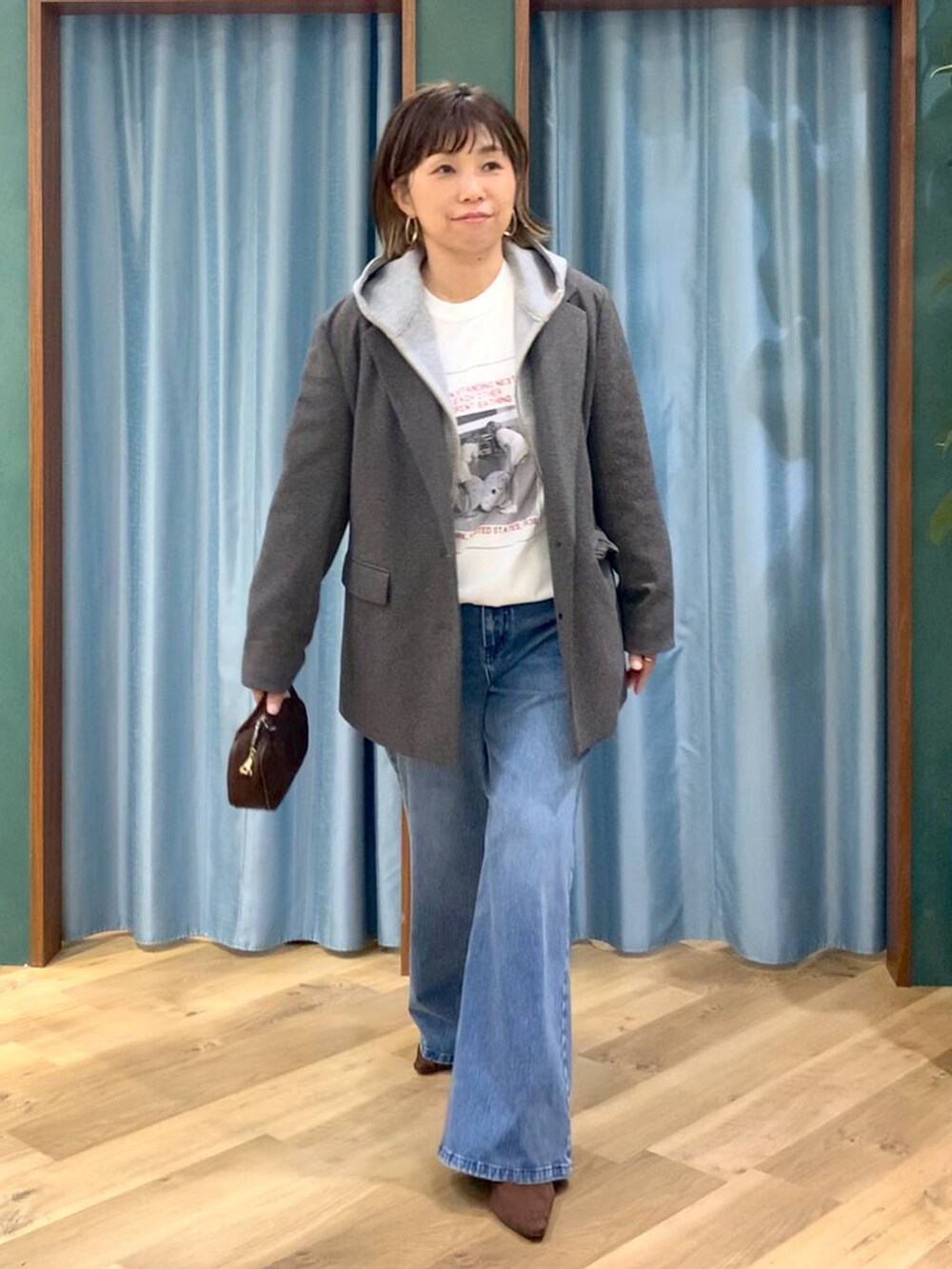 ブルー系のデニムパンツ、ブラウン系のテーラードジャケット、グレー系のパーカーを着用したレディースの秋コーディネートの5枚目の写真