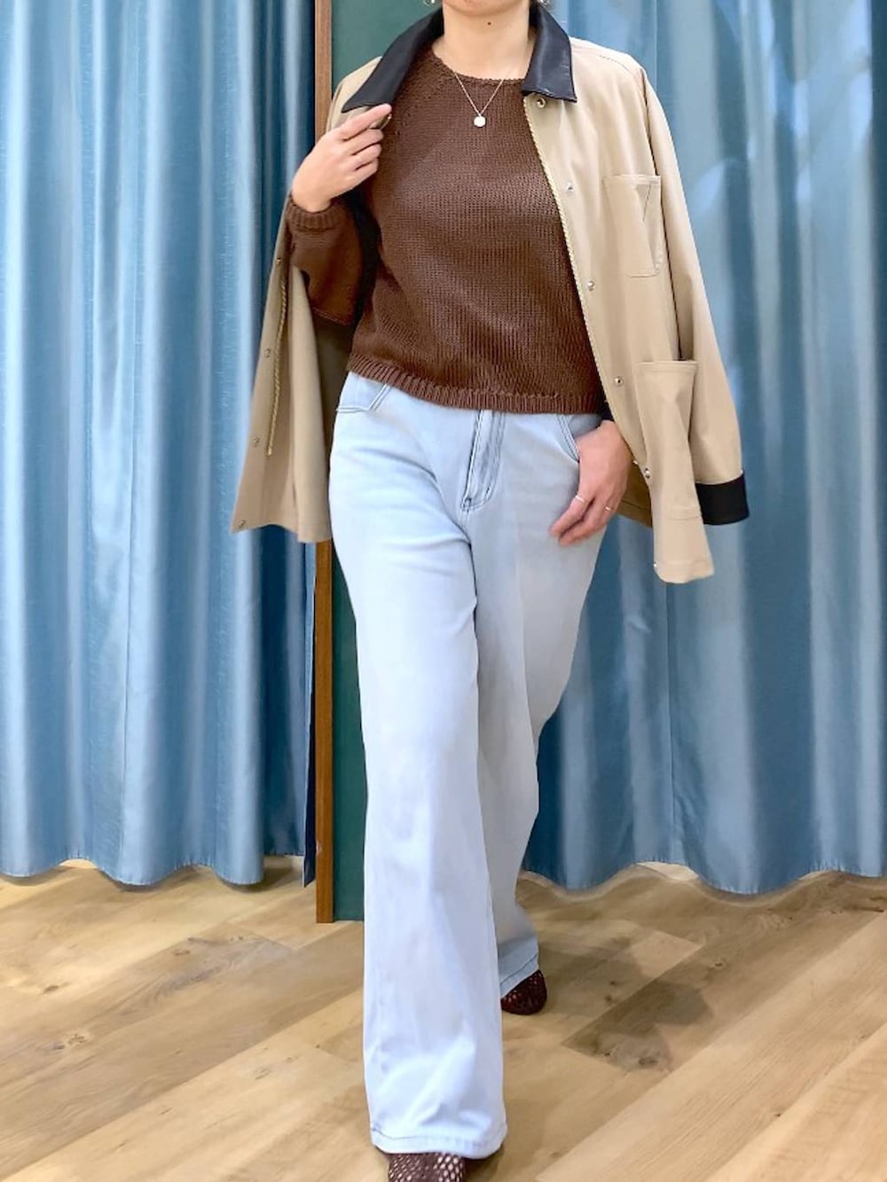 ブルー系のデニムパンツ、ブラウン系のニット/セーター、ベージュ系のカバーオールを着用したレディースの春コーディネートの5枚目の写真