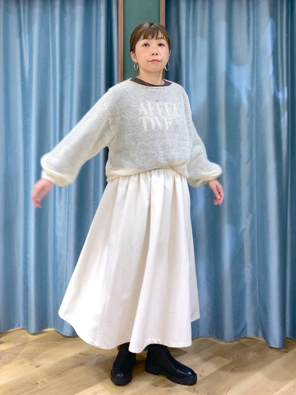 ブラック系のブーツ、ホワイト系のスカート、ホワイト系のニット/セーターを着用したレディースの冬コーディネートの4枚目の写真