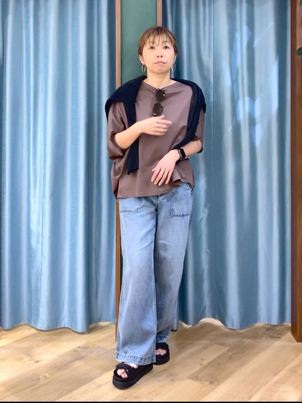 ブラウン系のTシャツ/カットソー、ブルー系のデニムパンツ、ブラック系のニット/セーターを着用したレディースの春コーディネートの4枚目の写真