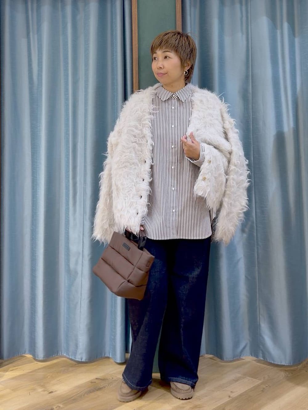 ベージュ系のシャツ/ブラウス、ブラウン系のトートバッグ、ブルー系のデニムパンツを着用したレディースの秋コーディネートの3枚目の写真
