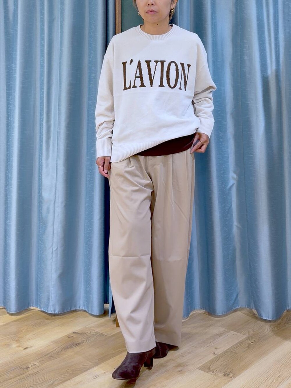 ブラウン系のTシャツ/カットソー、ブラウン系のブーツ、ホワイト系のニット/セーターを着用したレディースの秋コーディネートの6枚目の写真