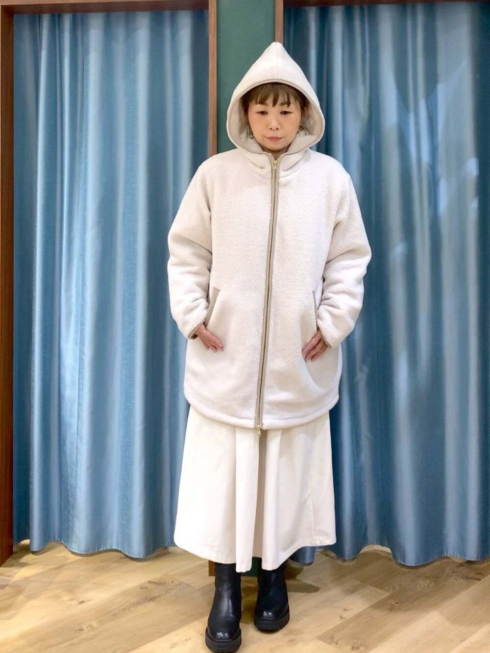 ブラック系のブーツ、ホワイト系のその他アウター、ホワイト系のスカートを着用したレディースの冬コーディネートの9枚目の写真