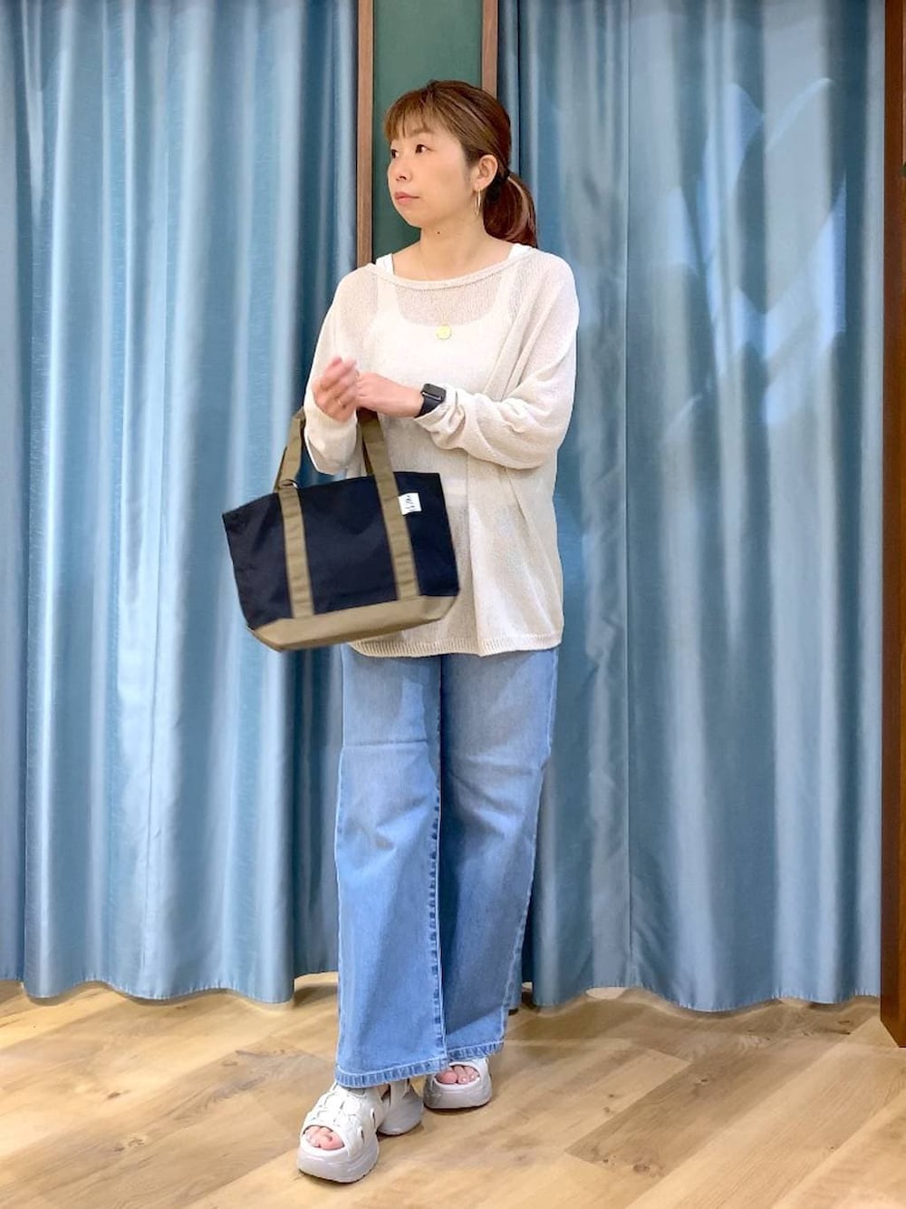 ブルー系のデニムパンツ、ホワイト系のタンクトップ、ホワイト系のニット/セーターを着用したレディースの春コーディネートの2枚目の写真