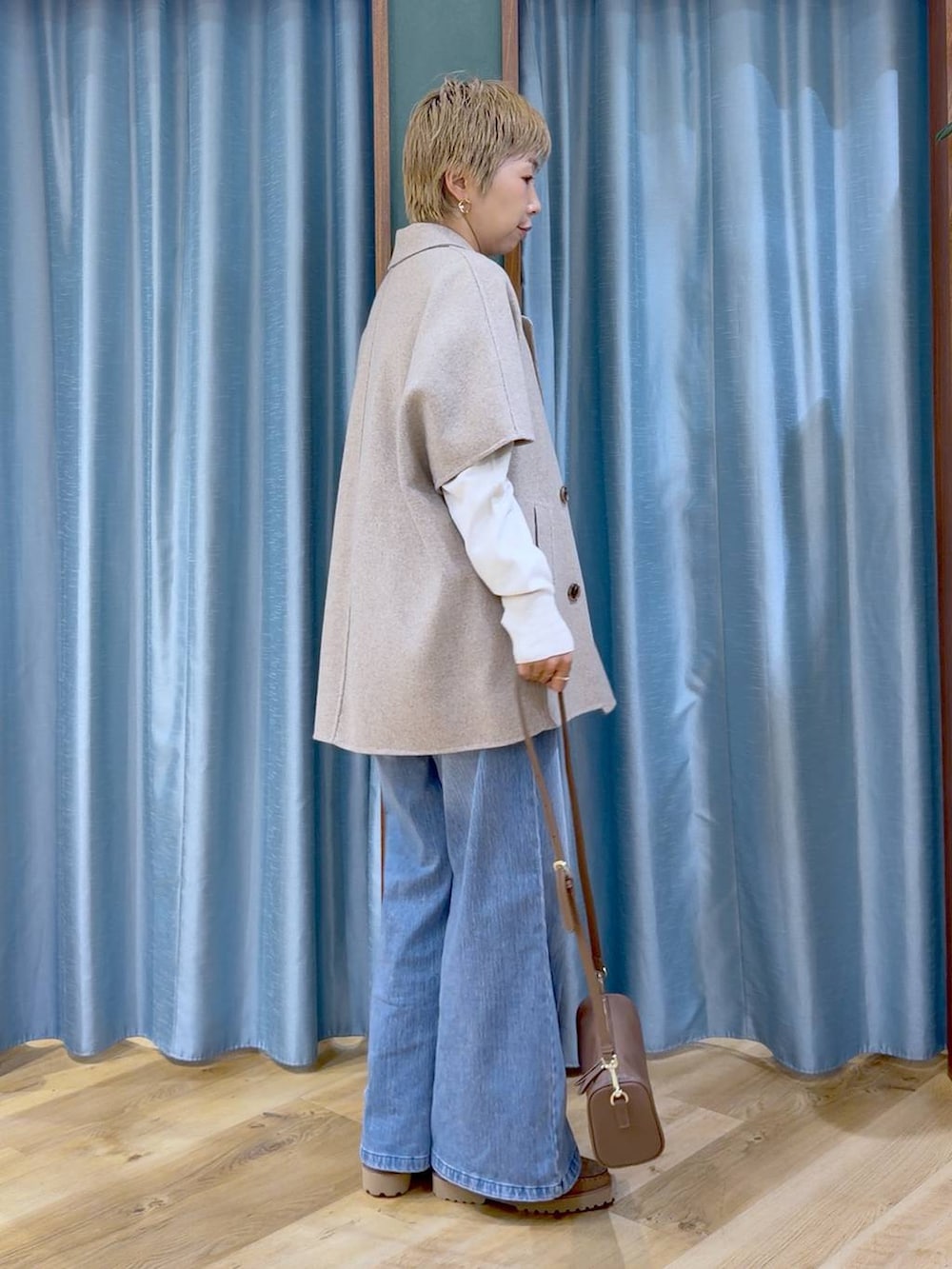 ブラウン系のハンドバッグ、ベージュ系のローファー、ブルー系のデニムパンツを着用したレディースの秋コーディネートの2枚目の写真