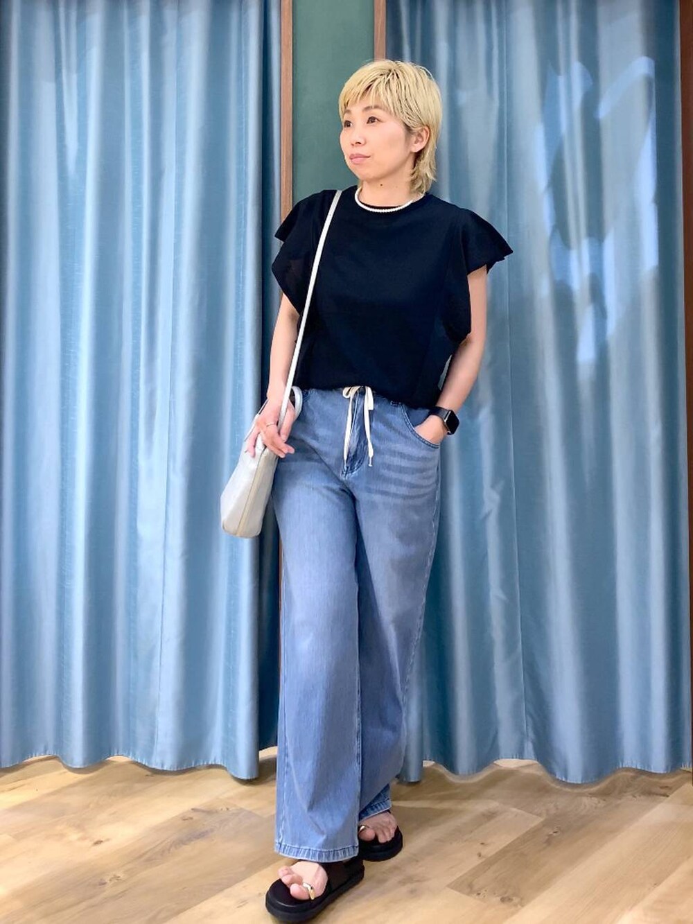 ブルー系のデニムパンツ、シルバー系のショルダーバッグ、ブラック系のニット/セーターを着用したレディースの夏コーディネートの2枚目の写真