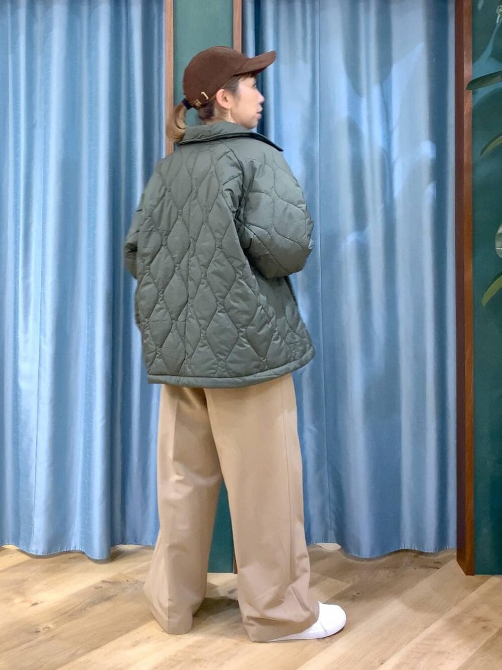 グリーン系のブルゾン、ブラウン系のニット/セーター、イエロー系のスラックスを着用したレディースの冬コーディネートの6枚目の写真