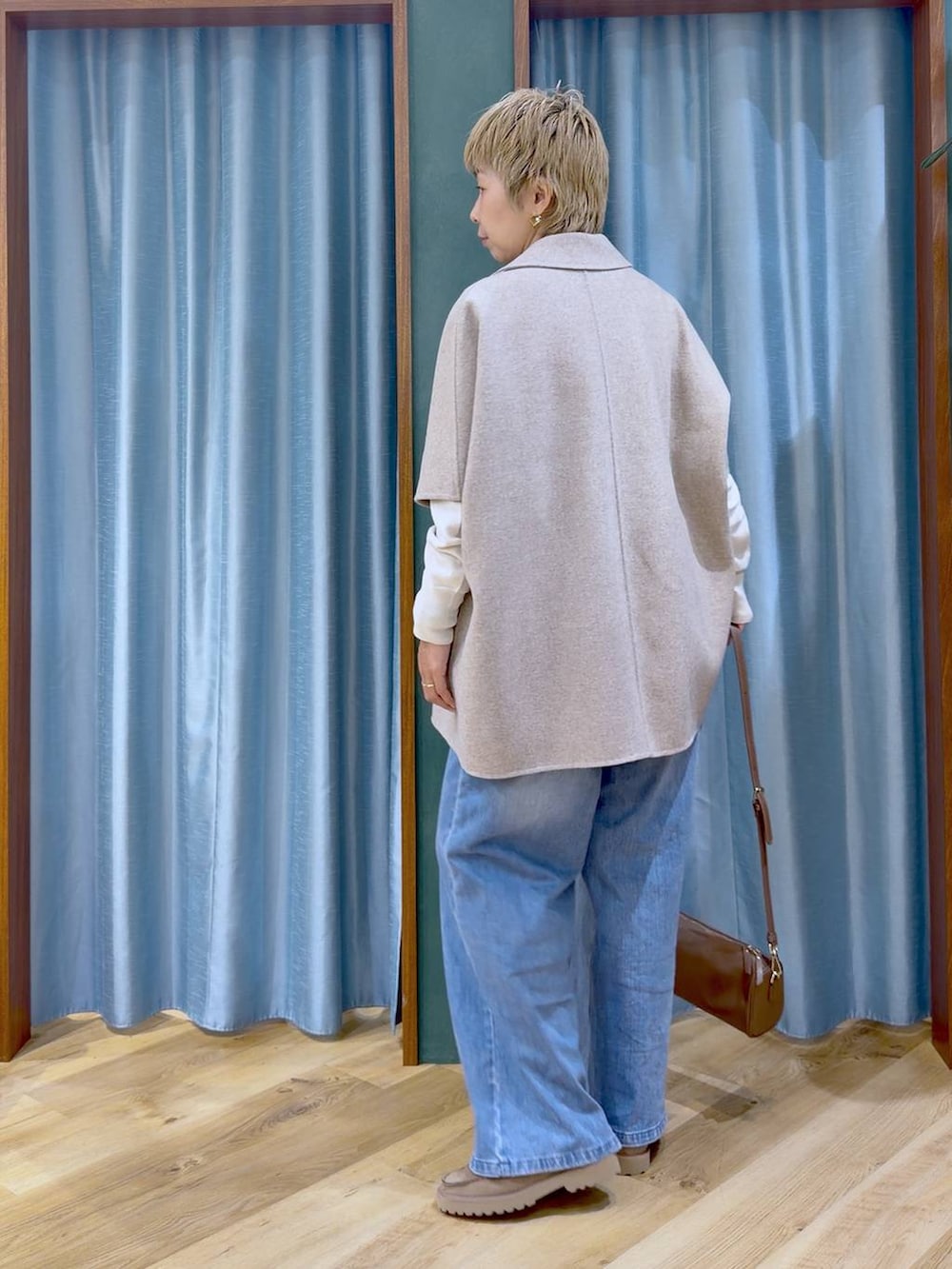 ブラウン系のハンドバッグ、ベージュ系のローファー、ブルー系のデニムパンツを着用したレディースの秋コーディネートの3枚目の写真