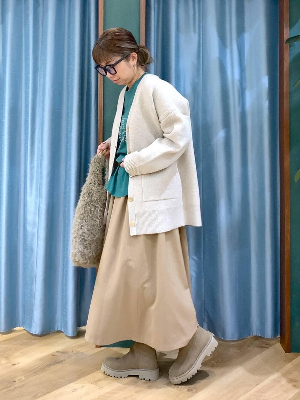 ベージュ系のハンドバッグ、ベージュ系のブーツ、グリーン系のTシャツ/カットソーを着用したレディースの冬コーディネートの2枚目の写真