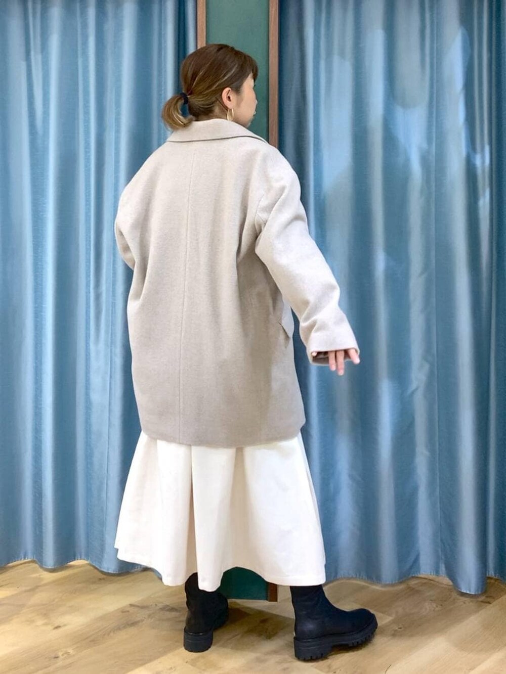 ブラック系のブーツ、ベージュ系のピーコート、ホワイト系のスカートを着用したレディースの冬コーディネートの5枚目の写真