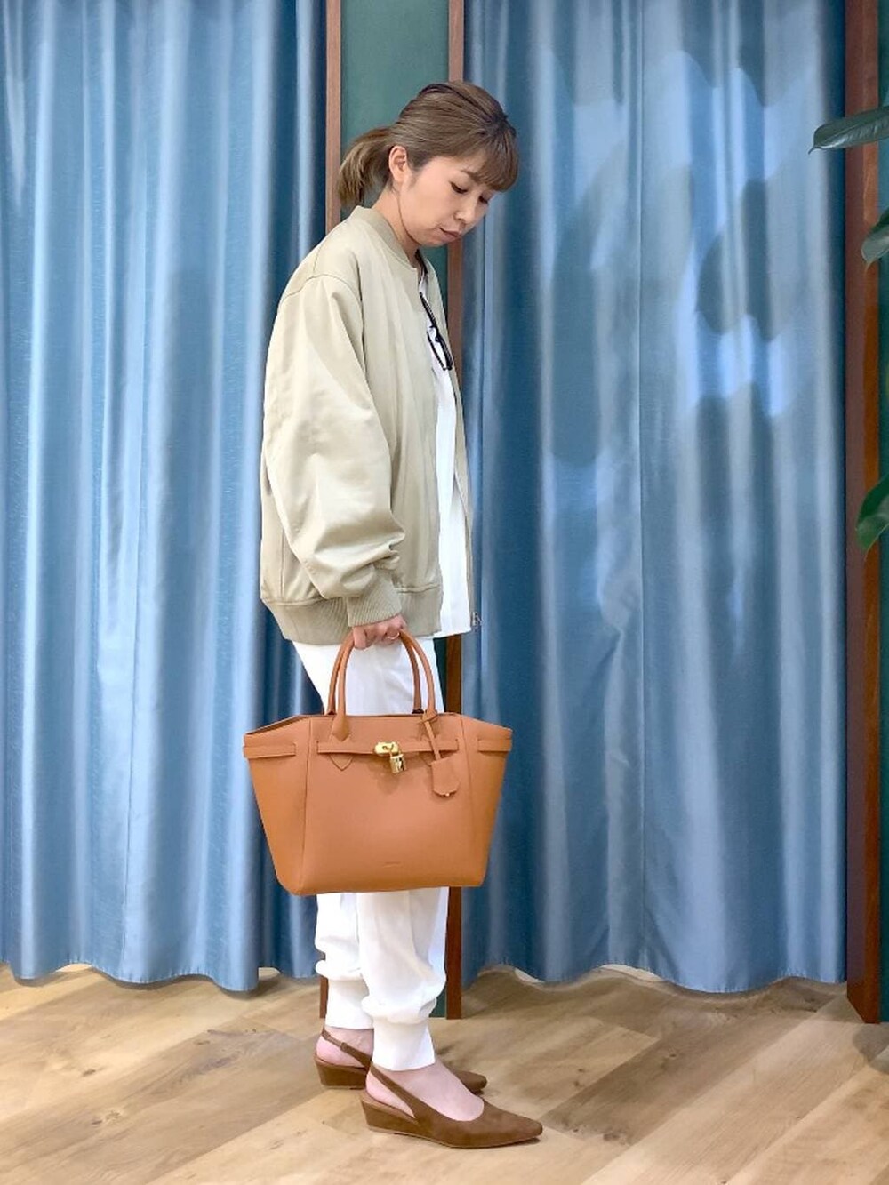 ベージュ系のMA-1、ホワイト系のTシャツ/カットソー、イエロー系のハンドバッグを着用したレディースの冬コーディネートの3枚目の写真