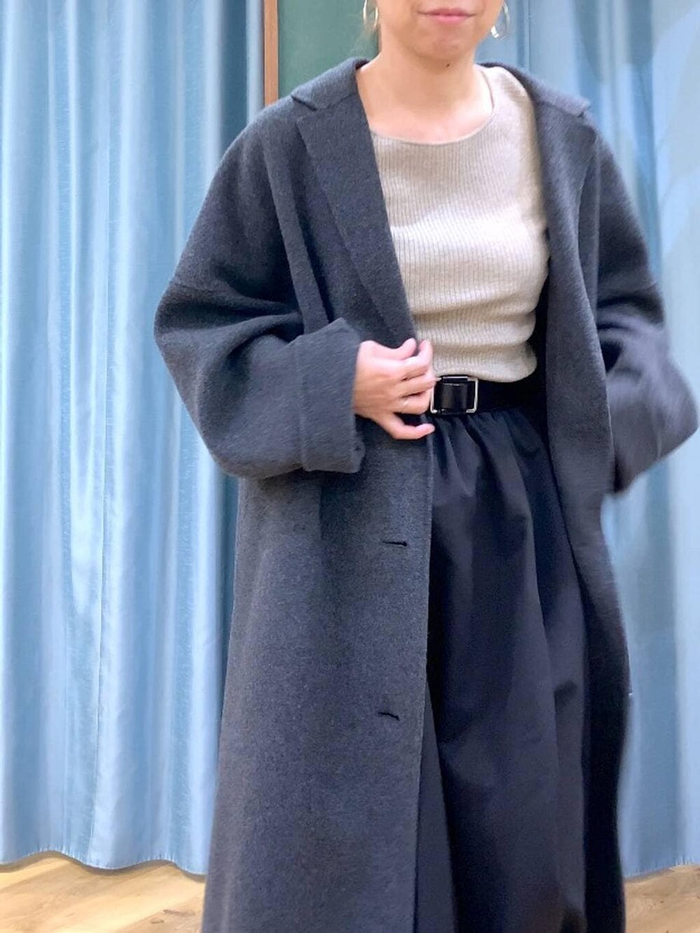 グレー系のチェスターコート、ブラック系のブーツ、ベージュ系のニット/セーターを着用したレディースの冬コーディネートの9枚目の写真
