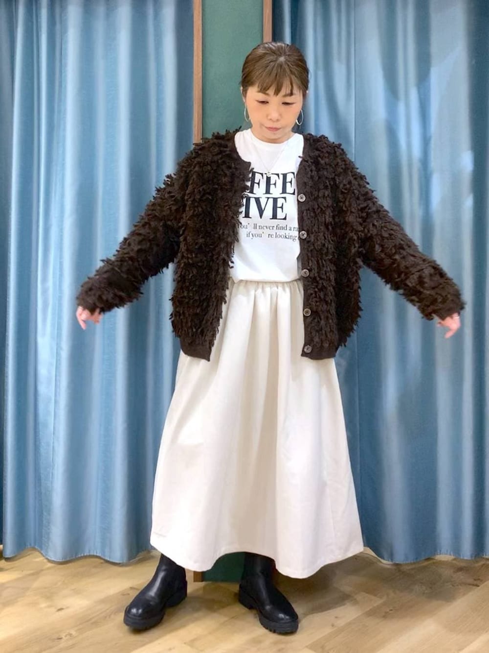 ブラック系のブーツ、ホワイト系のスカート、ブラウン系のカーディガン/ボレロを着用したレディースの冬コーディネートの5枚目の写真