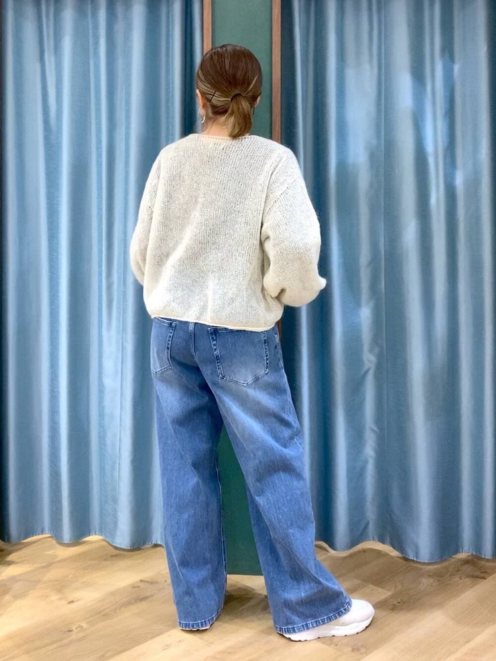 ブルー系のデニムパンツ、ホワイト系のニット/セーター、ホワイト系のスニーカーを着用したレディースの冬コーディネートの3枚目の写真