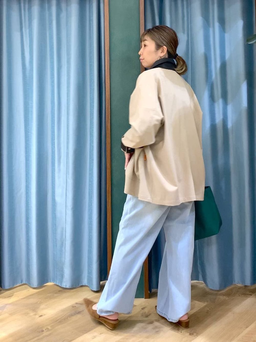 グリーン系のトートバッグ、ブルー系のデニムパンツ、ベージュ系のカバーオールを着用したレディースの冬コーディネートの5枚目の写真