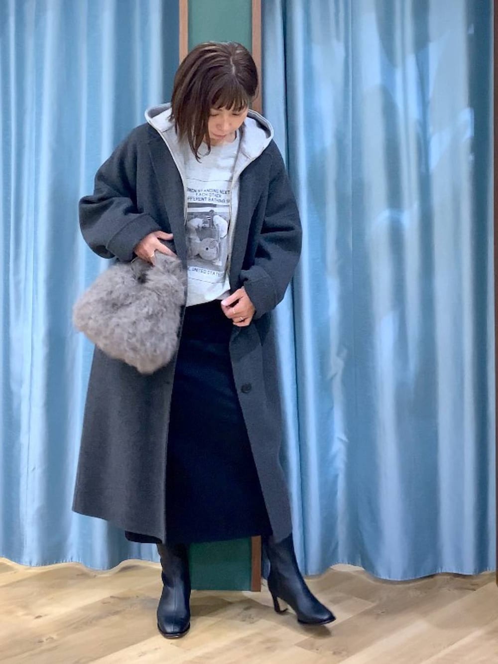 ブラウン系のトートバッグ、グレー系のチェスターコート、ブラック系のスカートを着用したレディースの秋コーディネートの7枚目の写真