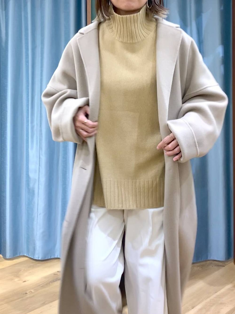 ベージュ系のニット/セーター、ベージュ系のチェスターコート、ブラック系のブーツを着用したレディースの秋コーディネートの6枚目の写真