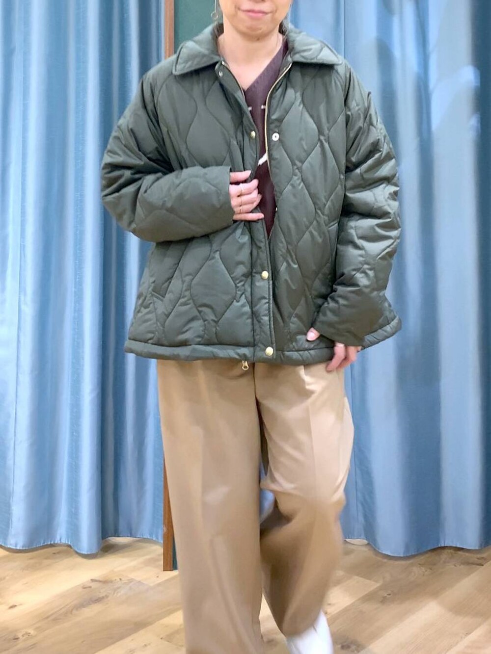 グリーン系のブルゾン、ブラウン系のニット/セーター、イエロー系のスラックスを着用したレディースの冬コーディネートの8枚目の写真