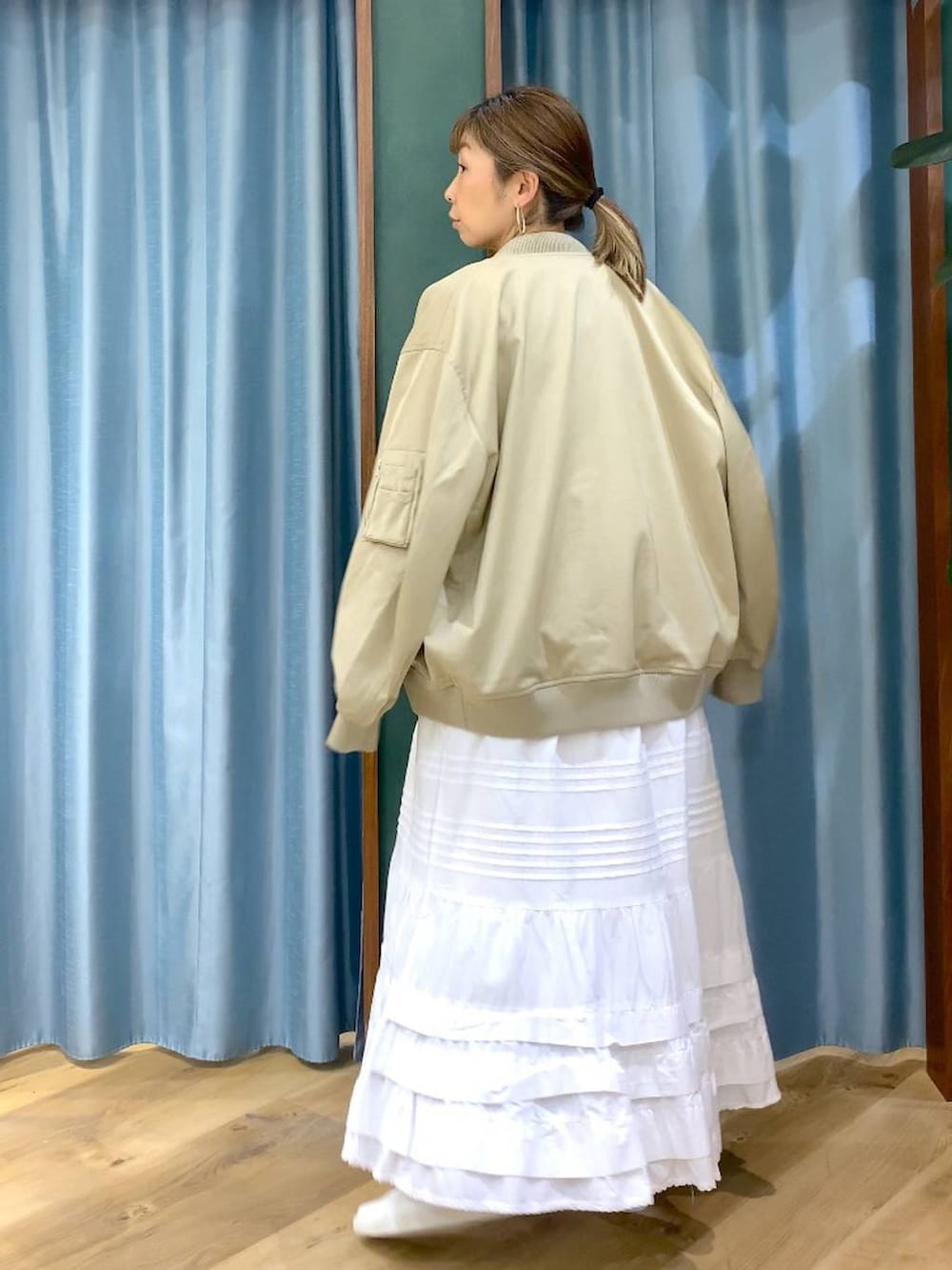 ベージュ系のMA-1、グレー系のシャツ/ブラウス、ホワイト系のスカートを着用したレディースの冬コーディネートの5枚目の写真