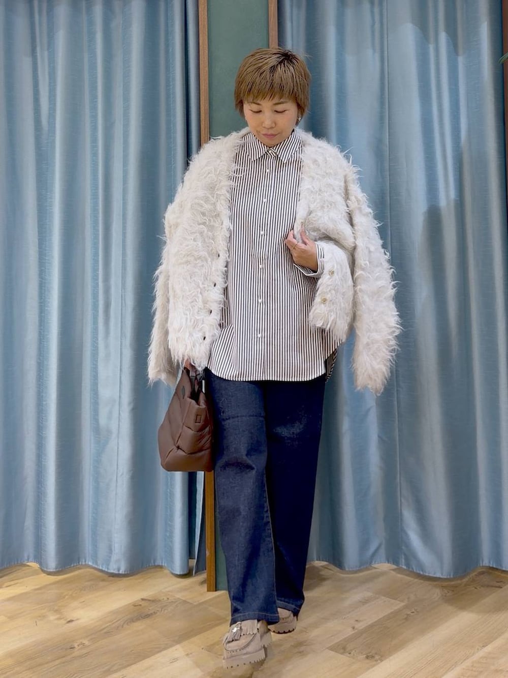ベージュ系のシャツ/ブラウス、ブラウン系のトートバッグ、ブルー系のデニムパンツを着用したレディースの秋コーディネートの8枚目の写真