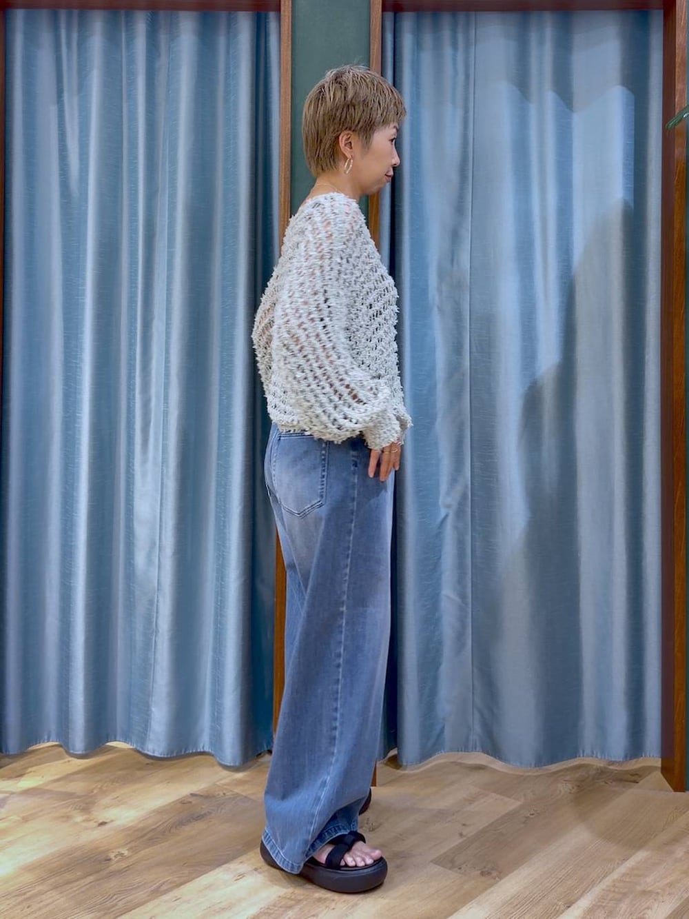 グレー系のタンクトップ、ブルー系のデニムパンツ、ブラック系のサンダルを着用したレディースの夏コーディネートの3枚目の写真