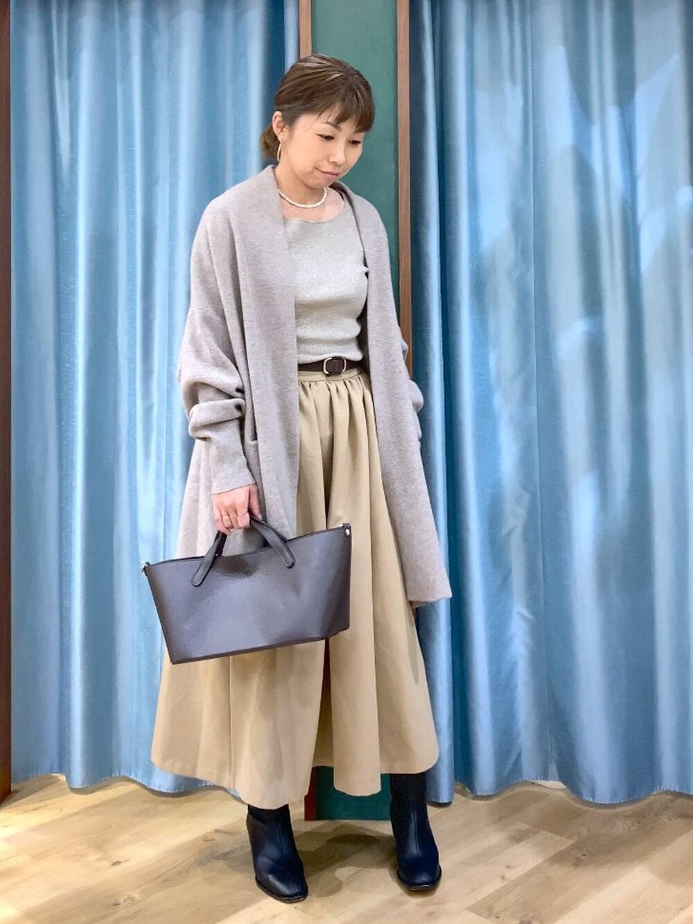 ブラック系のブーツ、ベージュ系のニット/セーター、ブラウン系のショルダーバッグを着用したレディースの秋コーディネートの4枚目の写真