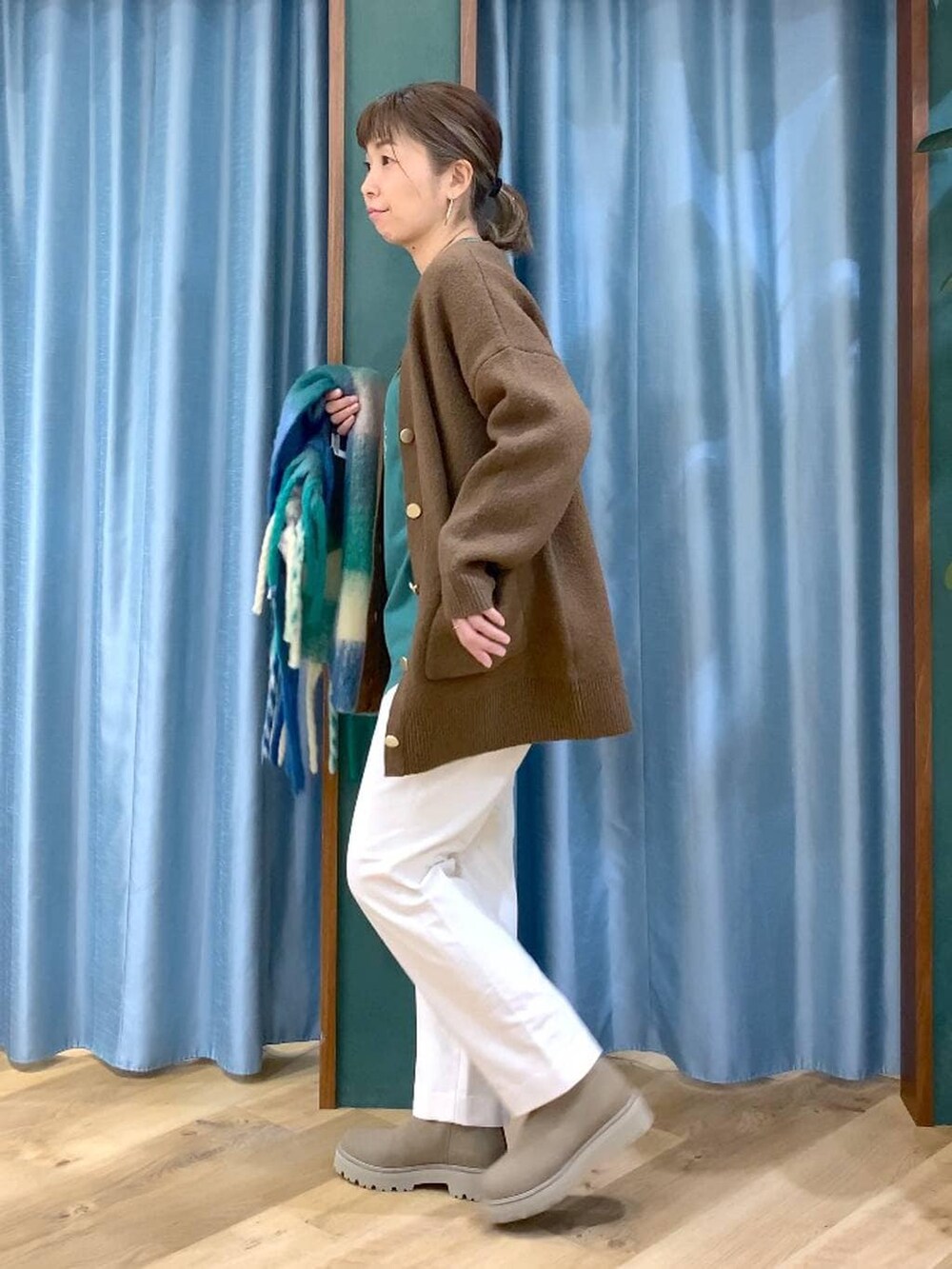 ベージュ系のブーツ、グリーン系のTシャツ/カットソー、ホワイト系のスラックスを着用したレディースの冬コーディネートの3枚目の写真