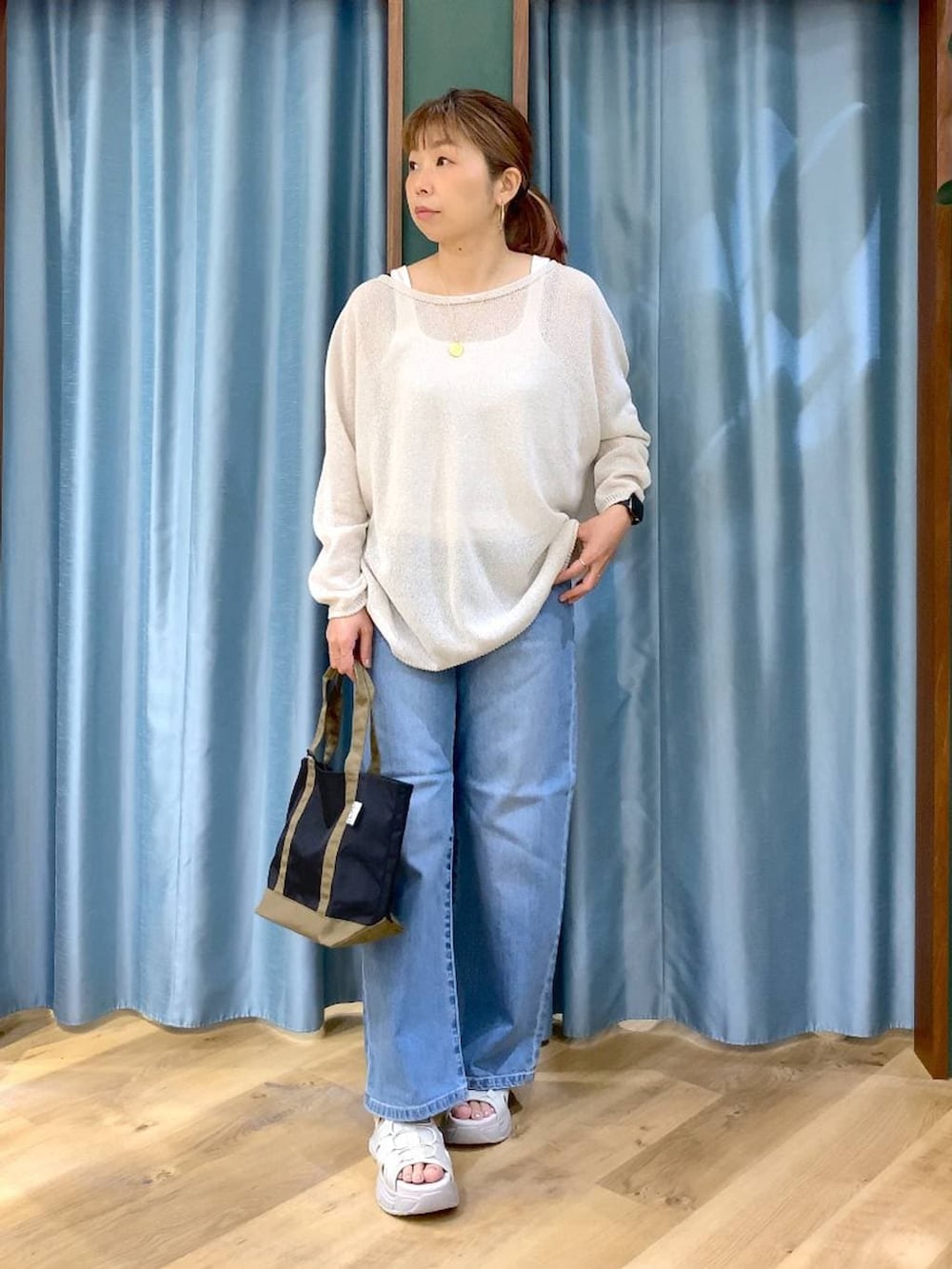 ブルー系のデニムパンツ、ホワイト系のタンクトップ、ホワイト系のニット/セーターを着用したレディースの春コーディネートの3枚目の写真