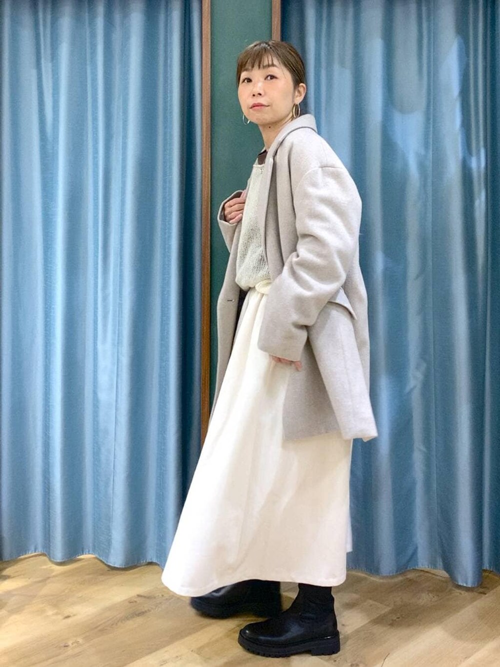 ブラック系のブーツ、ベージュ系のピーコート、ホワイト系のスカートを着用したレディースの冬コーディネートの2枚目の写真