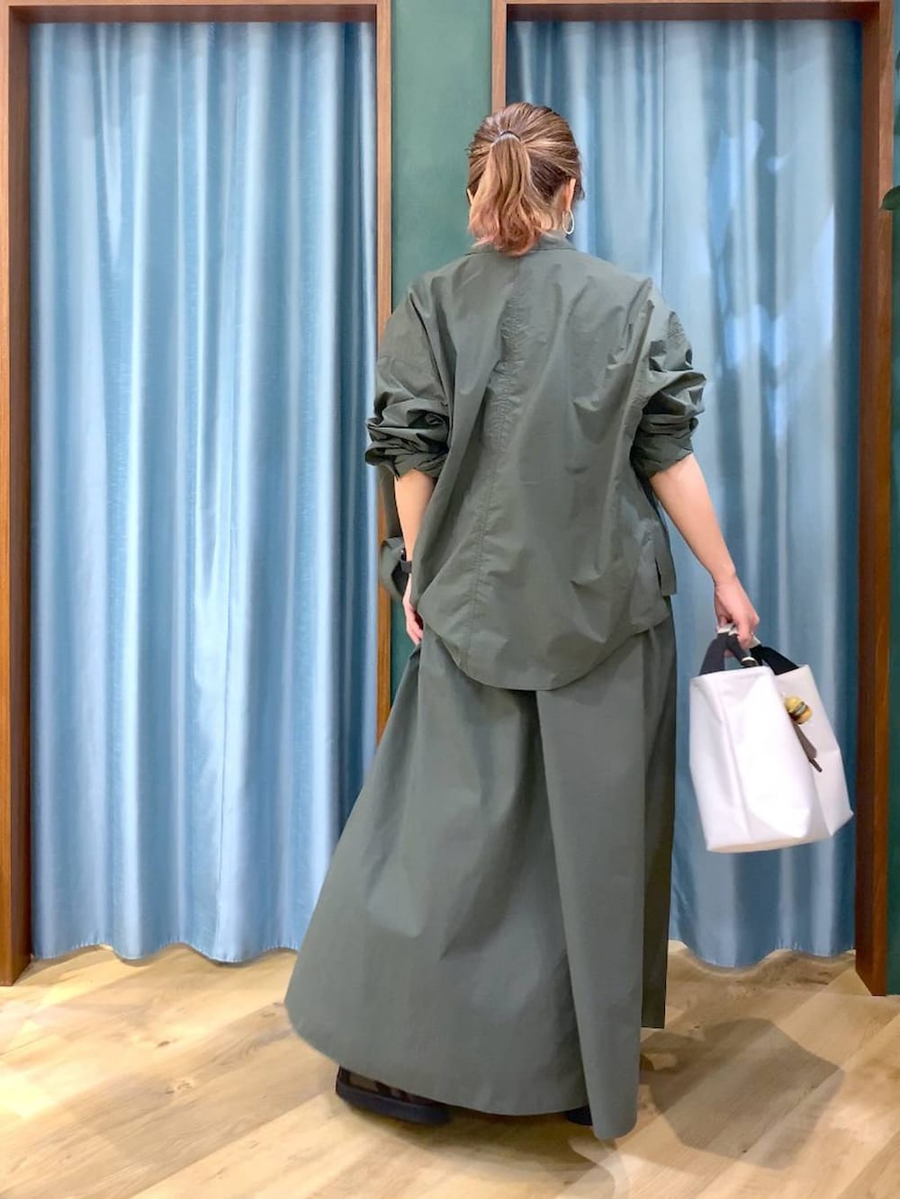 ホワイト系のトートバッグ、グリーン系のシャツ/ブラウス、ホワイト系のTシャツ/カットソーを着用したレディースの春コーディネートの6枚目の写真