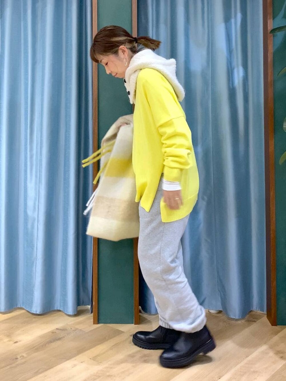 ブラック系のブーツ、ホワイト系のTシャツ/カットソー、イエロー系のニット/セーターを着用したレディースの秋コーディネートの2枚目の写真