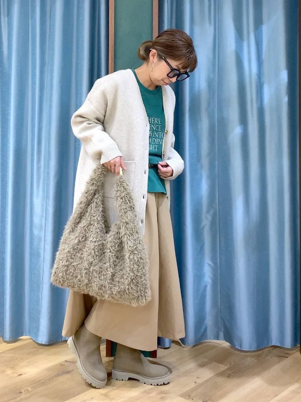 ベージュ系のハンドバッグ、ベージュ系のブーツ、グリーン系のTシャツ/カットソーを着用したレディースの冬コーディネートの3枚目の写真