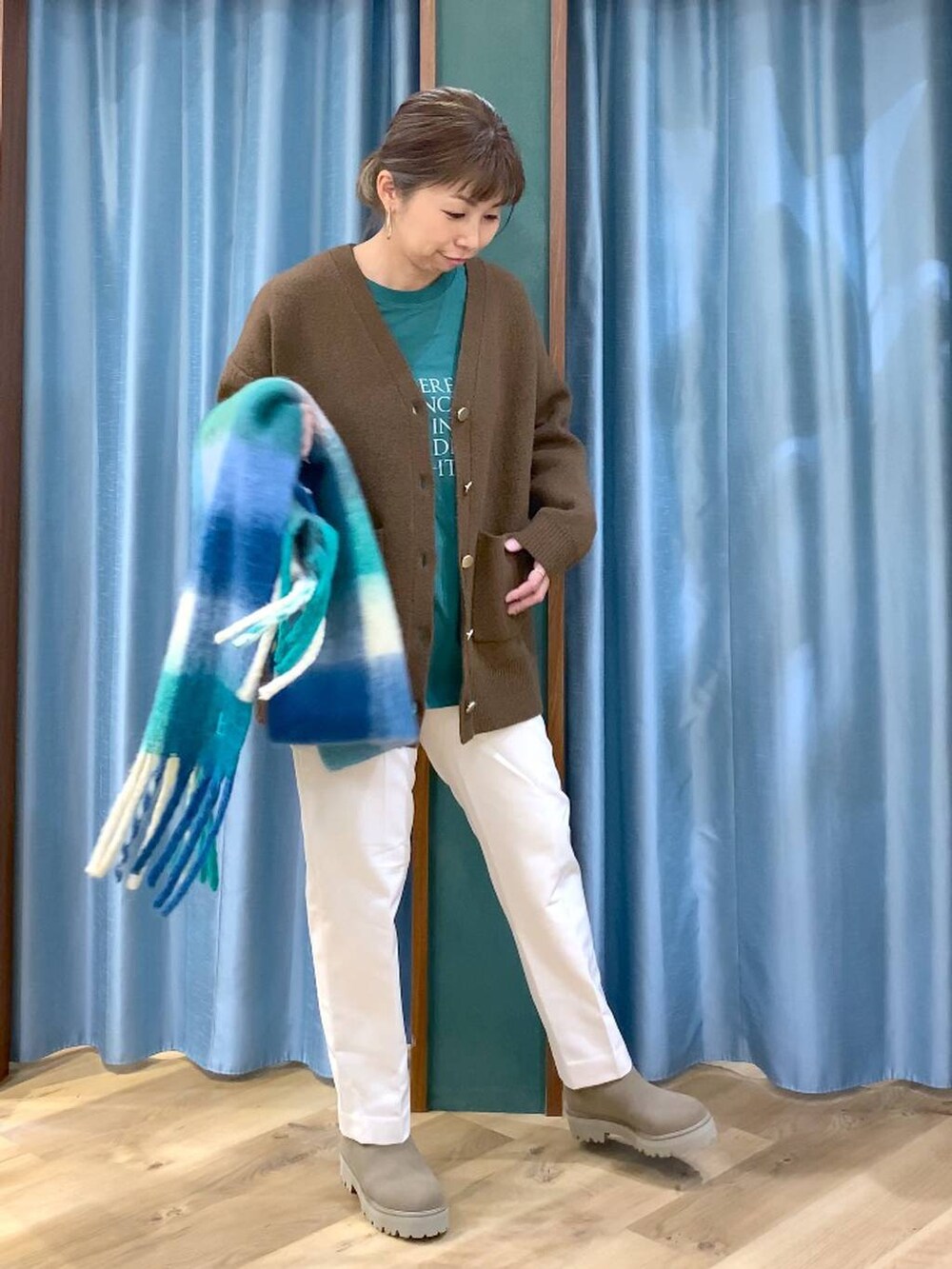 ベージュ系のブーツ、グリーン系のTシャツ/カットソー、ホワイト系のスラックスを着用したレディースの冬コーディネートの4枚目の写真