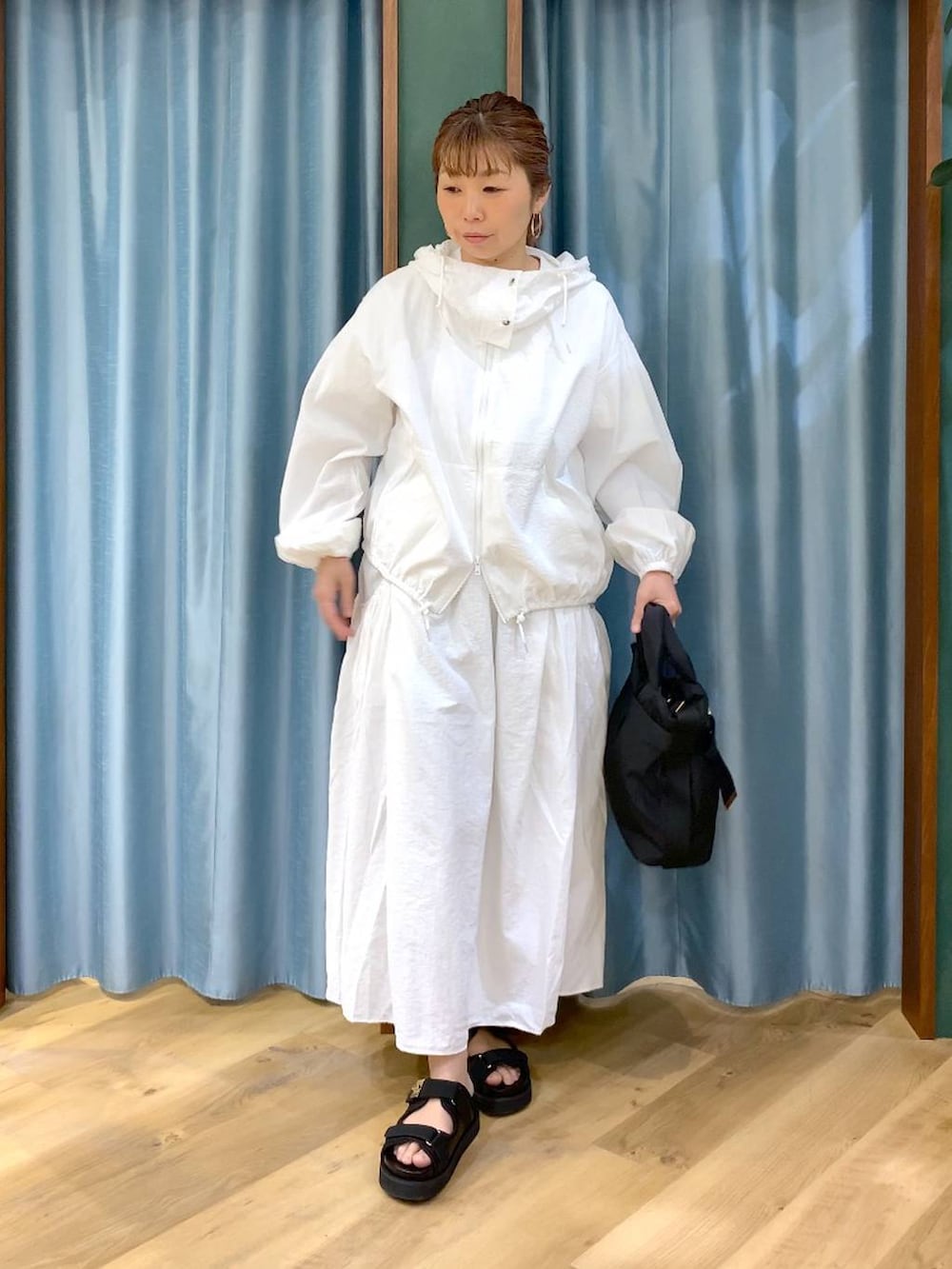 ホワイト系のスカート、ホワイト系のブルゾン、ブラック系のトートバッグを着用したレディースの春コーディネートの4枚目の写真