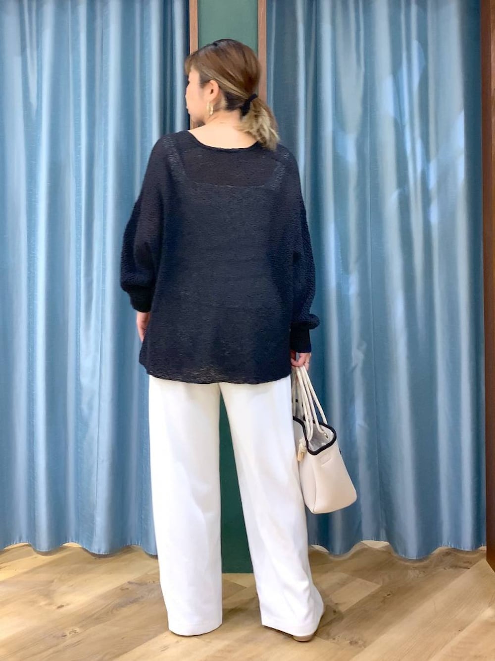 ホワイト系のスラックス、ブラック系のカーディガン/ボレロ、ホワイト系のトートバッグを着用したレディースの春コーディネートの6枚目の写真