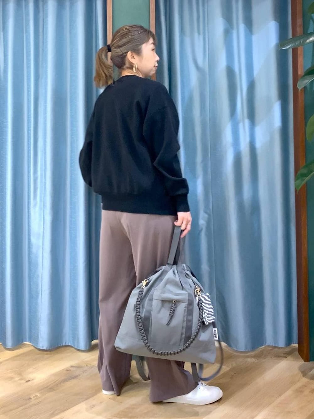 グリーン系のスラックス、ブラック系のカーディガン/ボレロ、グレー系のバックパック/リュックを着用したレディースの冬コーディネートの6枚目の写真