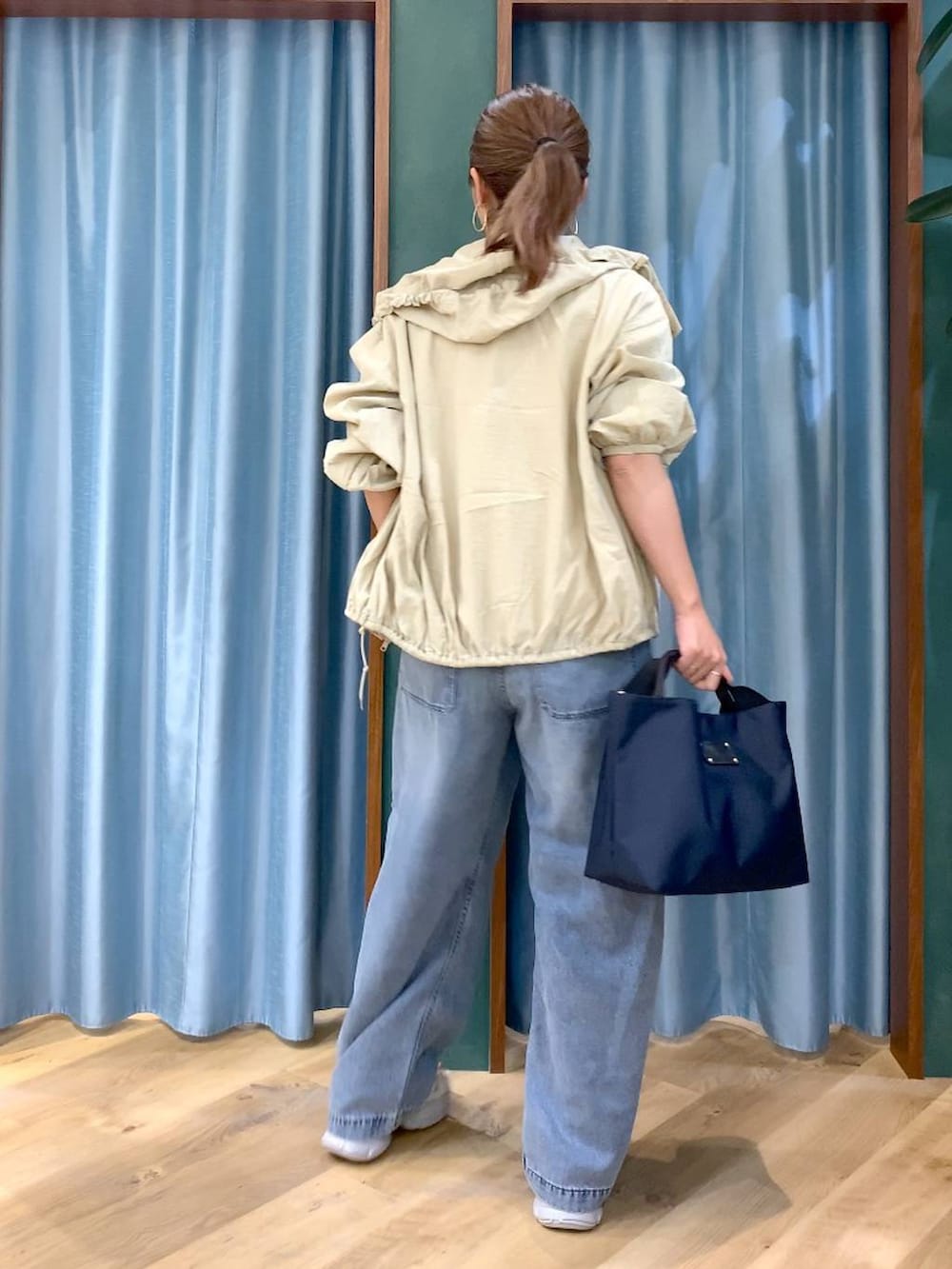 ブルー系のトートバッグ、ブルー系のデニムパンツ、ベージュ系のブルゾンを着用したレディースの春コーディネートの3枚目の写真