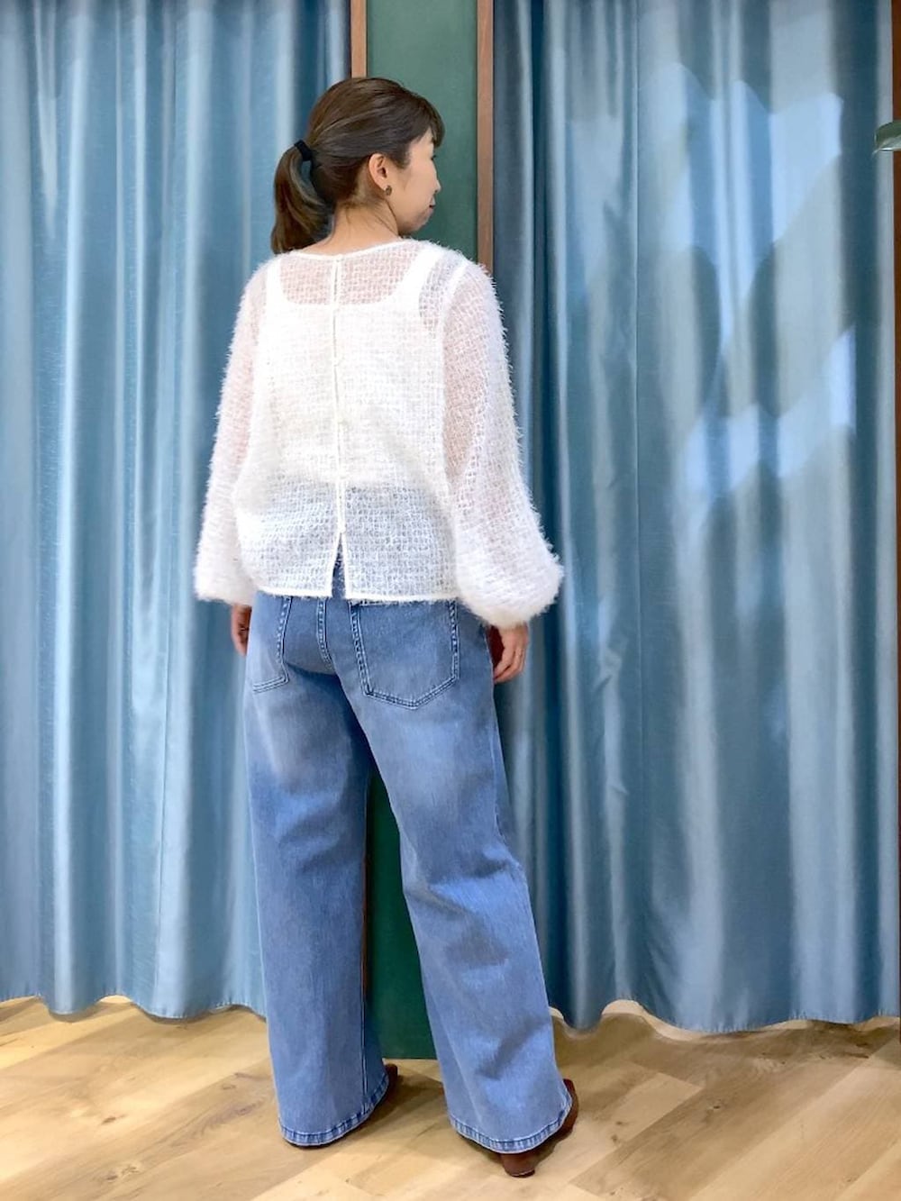 ブラウン系のパンプス、ホワイト系のタンクトップ、ブルー系のデニムパンツを着用したレディースの冬コーディネートの4枚目の写真