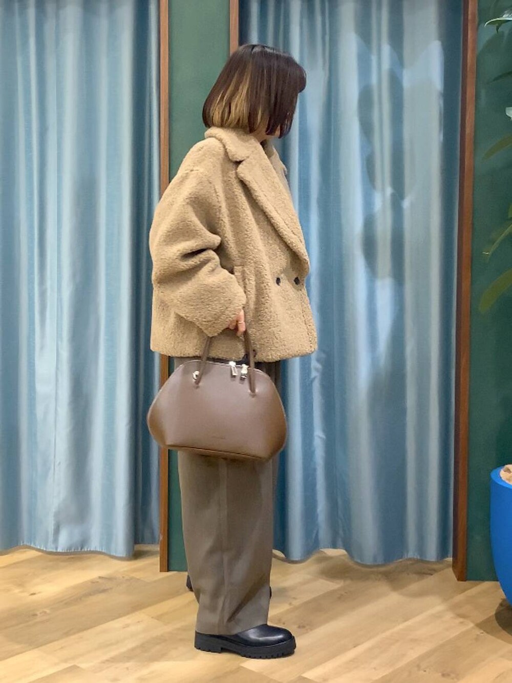 ブラック系のブーツ、ベージュ系のピーコート、ブラウン系のトートバッグを着用したレディースの秋コーディネートの3枚目の写真