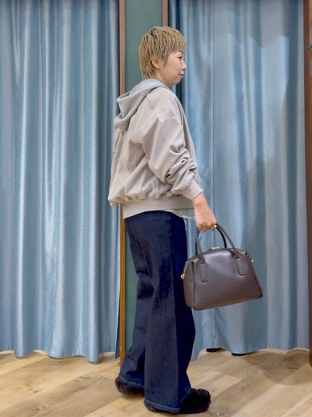ブラウン系のその他シューズ、ブラウン系のボストンバッグ、ブルー系のデニムパンツを着用したレディースの秋コーディネートの4枚目の写真