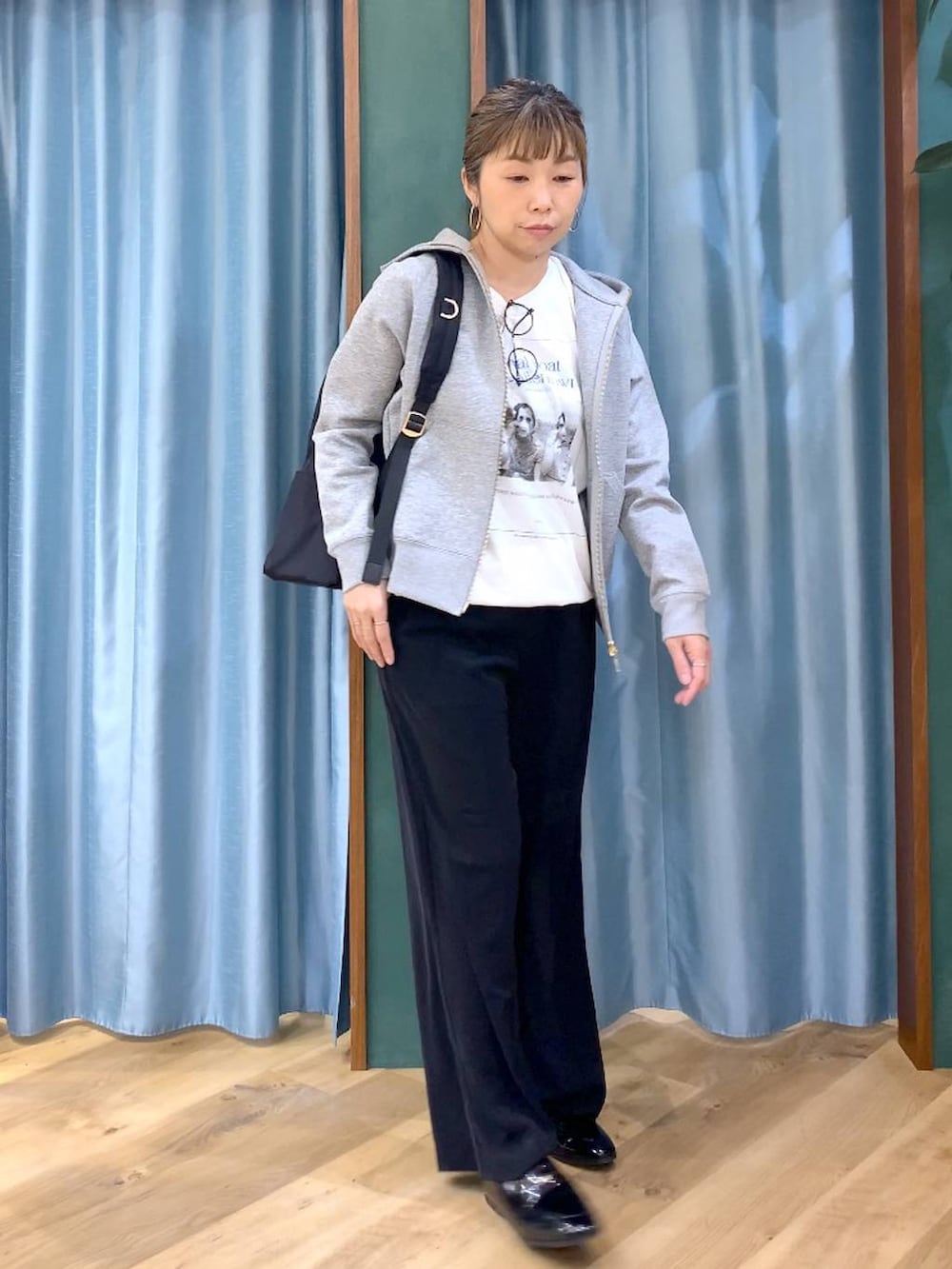 ブラック系のバックパック/リュック、ブラック系のスラックス、グレー系のパーカーを着用したレディースの春コーディネートの2枚目の写真