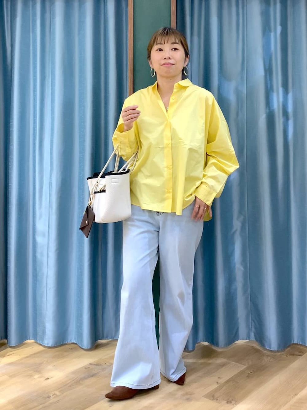 ブラウン系のパンプス、ブルー系のデニムパンツ、イエロー系のシャツ/ブラウスを着用したレディースの春コーディネートの3枚目の写真