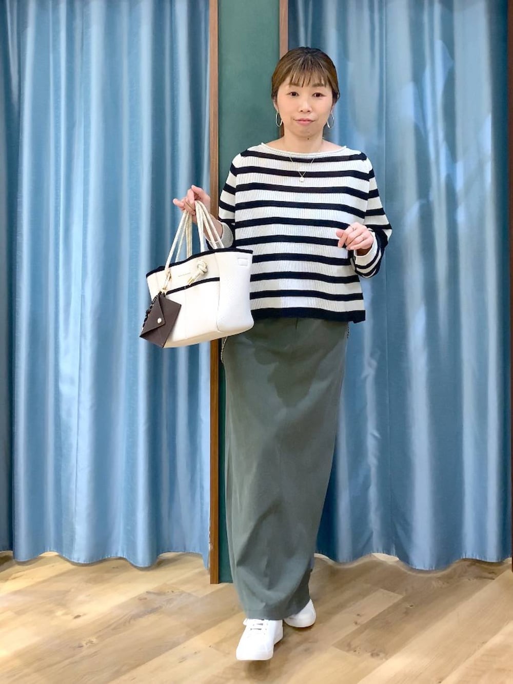 ベージュ系のニット/セーター、グリーン系のスカート、ホワイト系のトートバッグを着用したレディースの春コーディネートの5枚目の写真