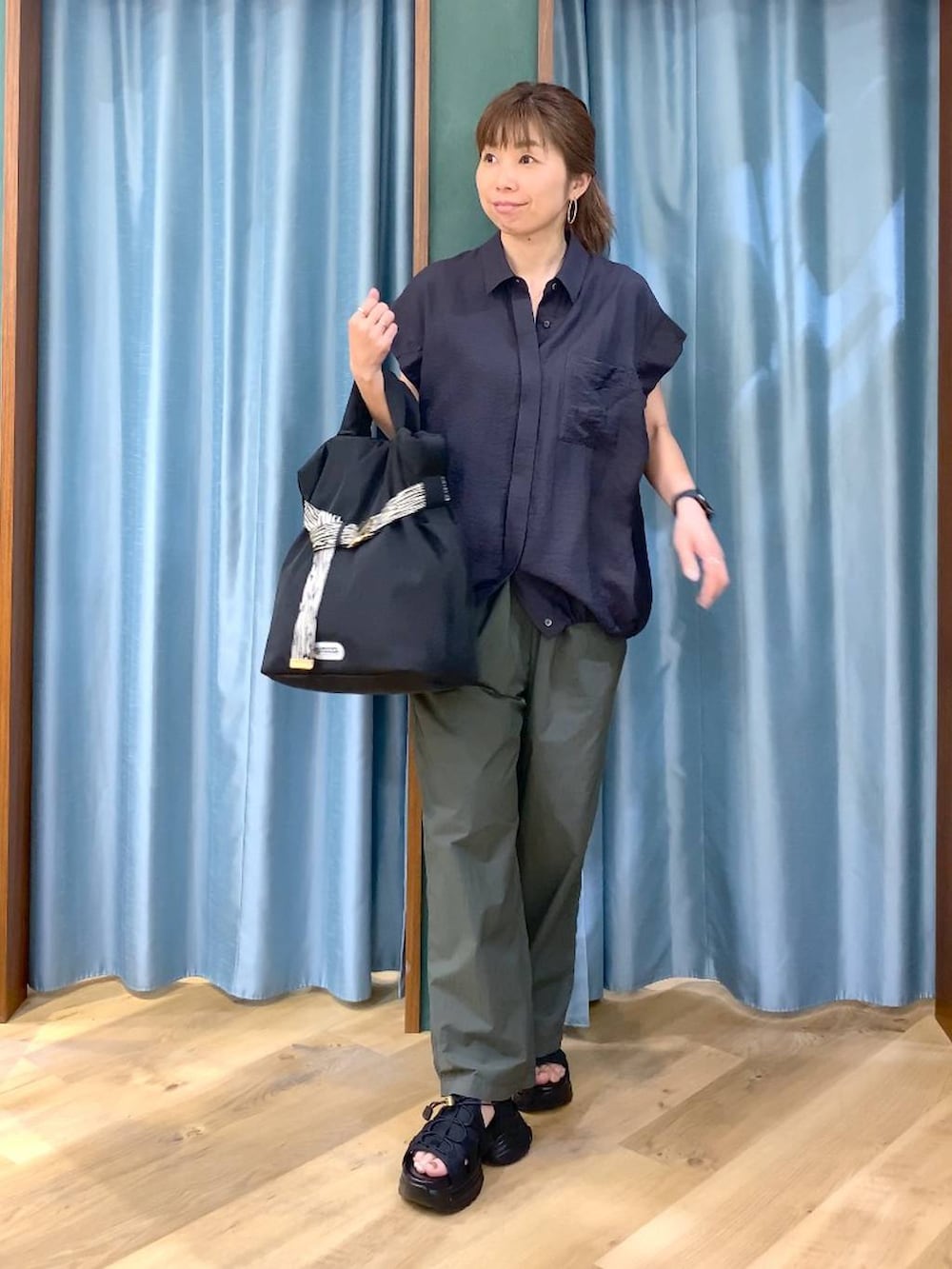 グリーン系のその他パンツ、ブラック系のトートバッグ、グレー系のシャツ/ブラウスを着用したレディースの春コーディネートの2枚目の写真