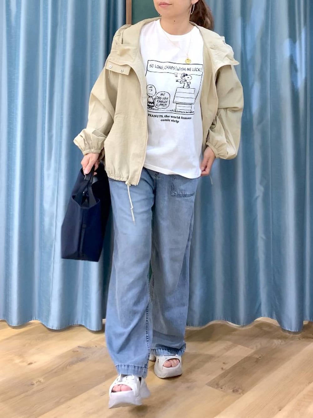 ブルー系のトートバッグ、ブルー系のデニムパンツ、ベージュ系のブルゾンを着用したレディースの春コーディネートの7枚目の写真