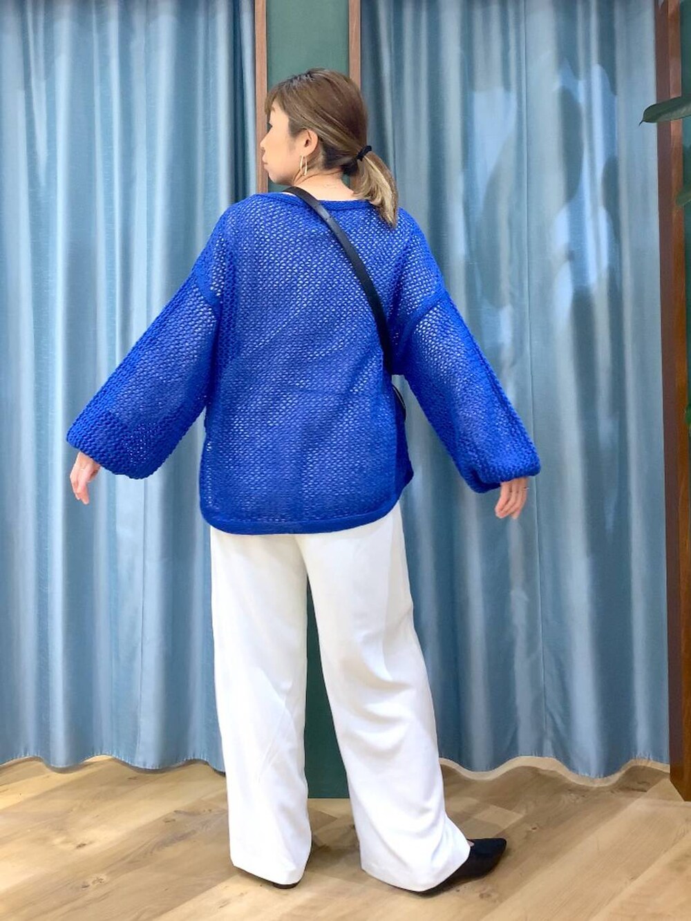 ホワイト系のスラックス、ブルー系のニット/セーター、ブラック系のパンプスを着用したレディースの冬コーディネートの6枚目の写真