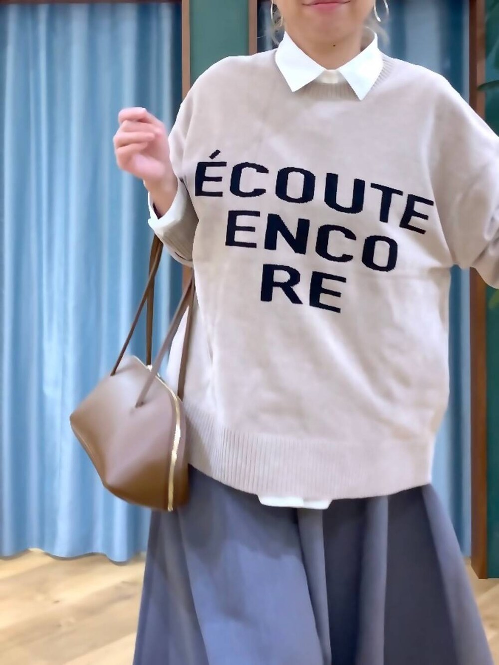 イエロー系のトートバッグ、ホワイト系のシャツ/ブラウス、ベージュ系のニット/セーターを着用したレディースの秋コーディネートの7枚目の写真