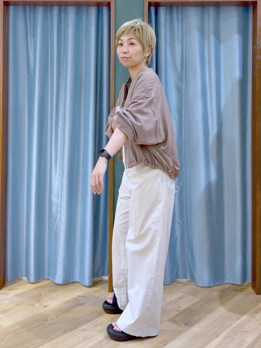イエロー系のブルゾン、ベージュ系のその他パンツ、ブラック系のサンダルを着用したレディースの夏コーディネートの3枚目の写真