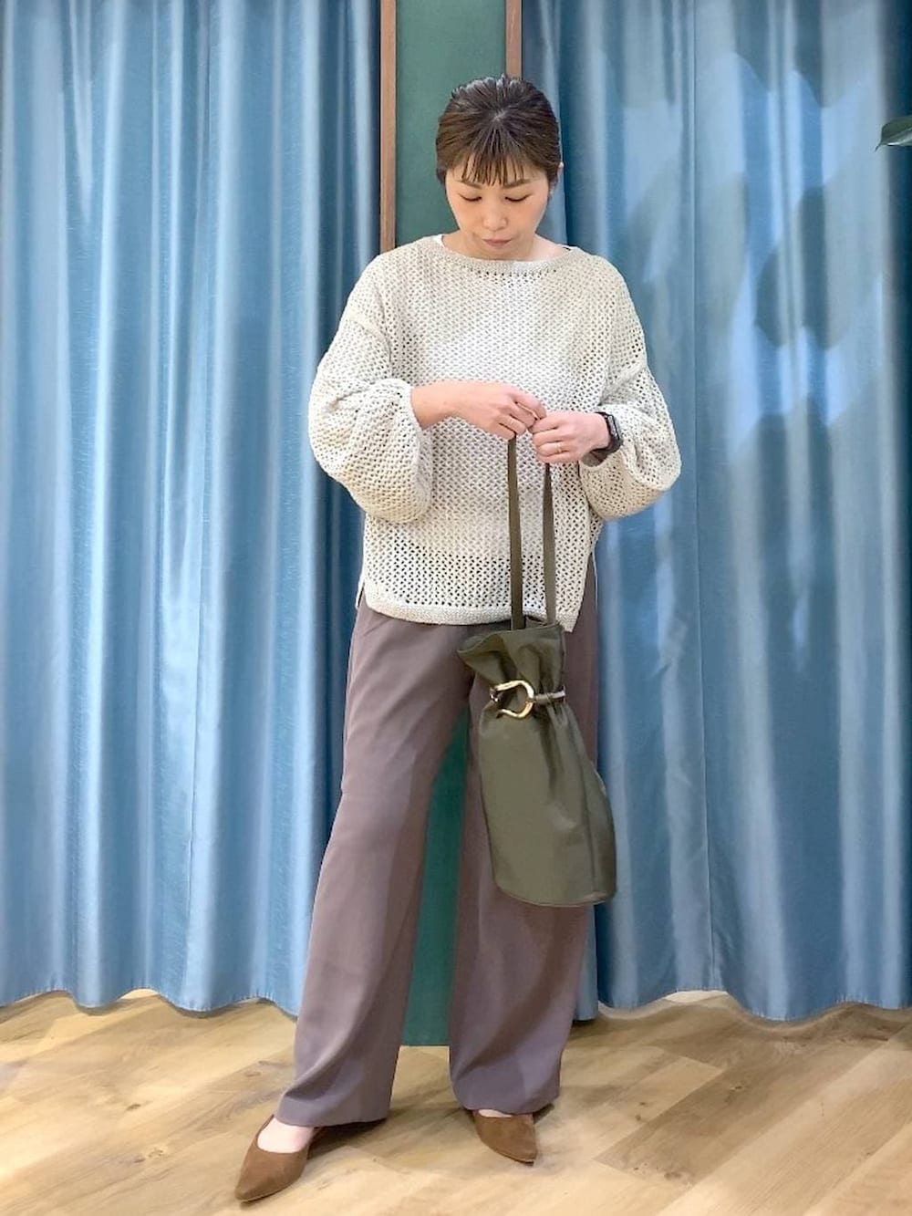 グリーン系のスラックス、ベージュ系のニット/セーター、ホワイト系のTシャツ/カットソーを着用したレディースの冬コーディネートの8枚目の写真